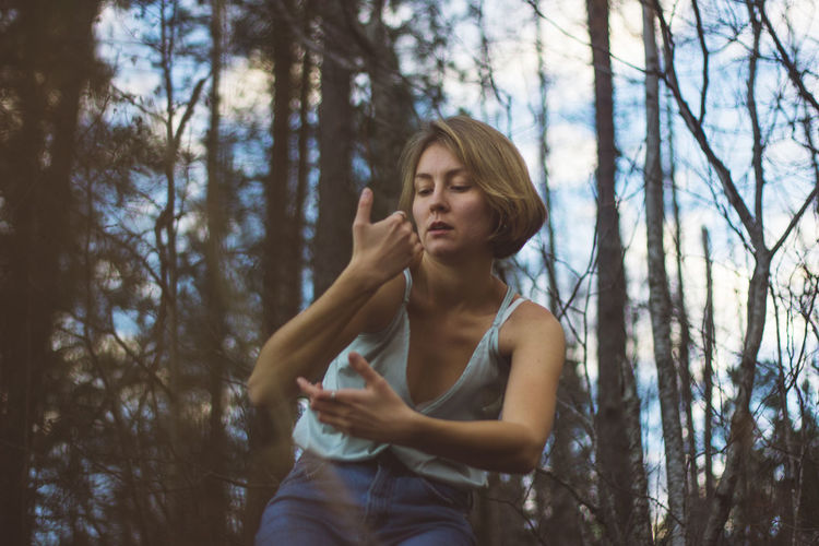 Low angle view of young woman dancing in forest