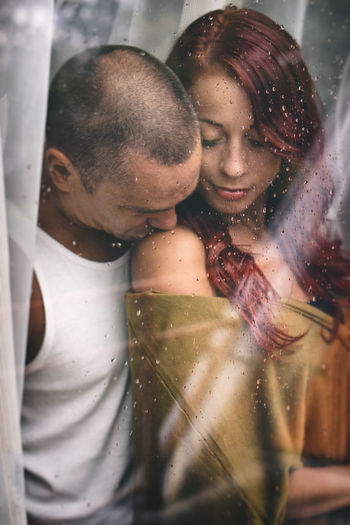 Couple romancing seen through window in house