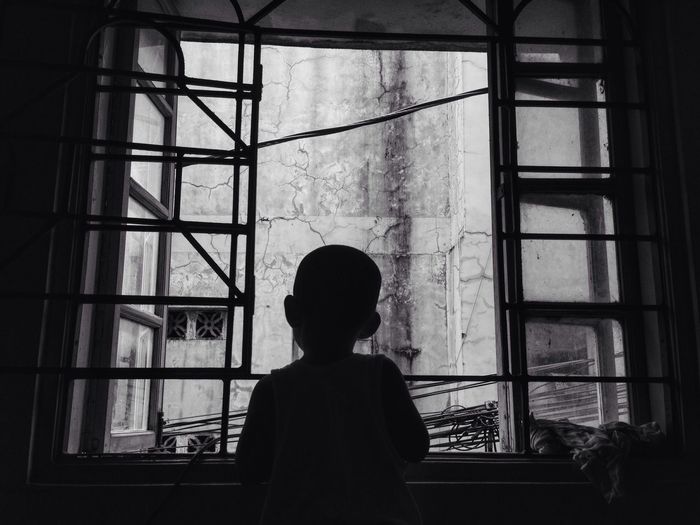 Boy looking through window at home