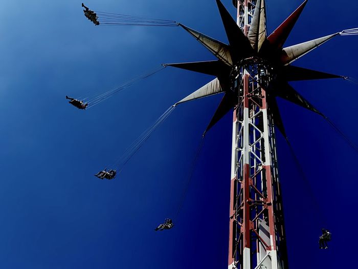 Low angle view of chain swing ride against blue sky