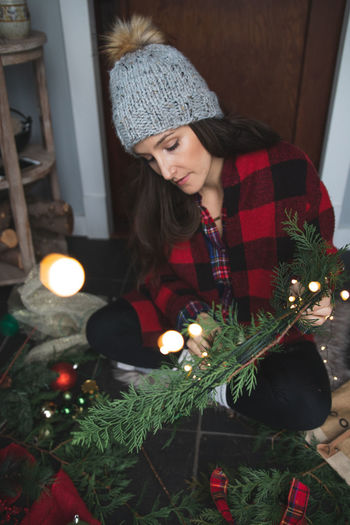 Midsection of woman in illuminated christmas tree at home