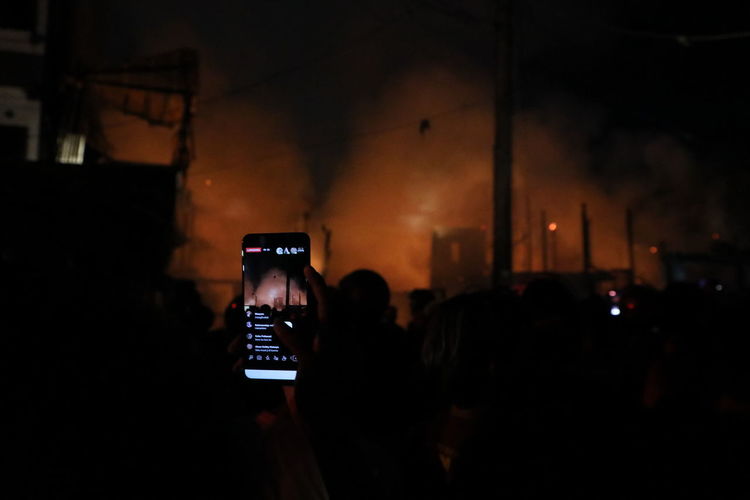 People photographing illuminated smart phone at night