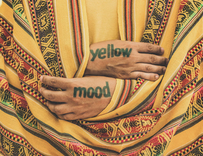 Midsection of man with yellow mood tattoo on hands