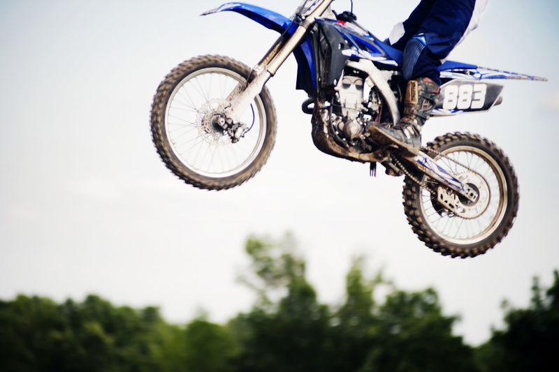 Low section of biker performing stunt in mid-air against clear sky