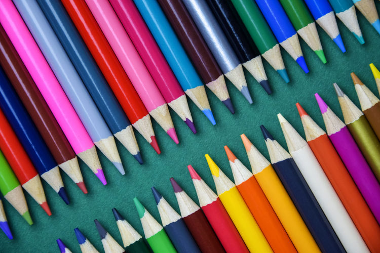 Color pencils on green background. arrangement of multicolored pencils. top view. close-up.