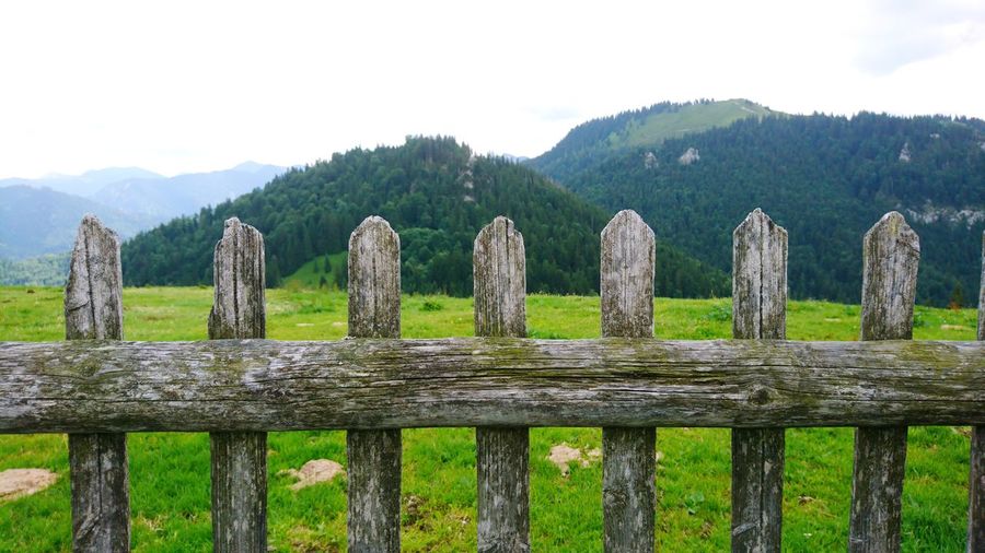 Wooden fence on landscape against sky
