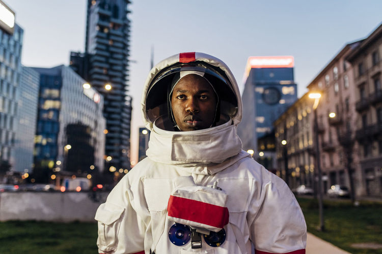 Serious male astronaut standing in front of of building