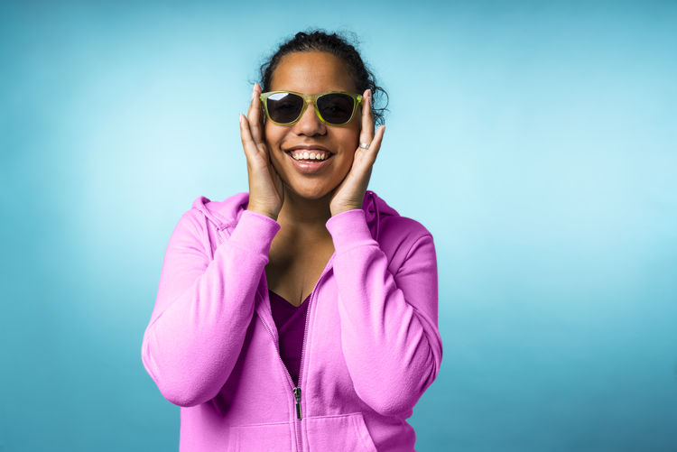Young attractive mixed race woman with sunglasses in a blue background
