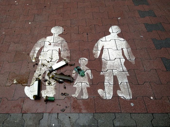 High angle view of shattered wine bottle on family sign over footpath