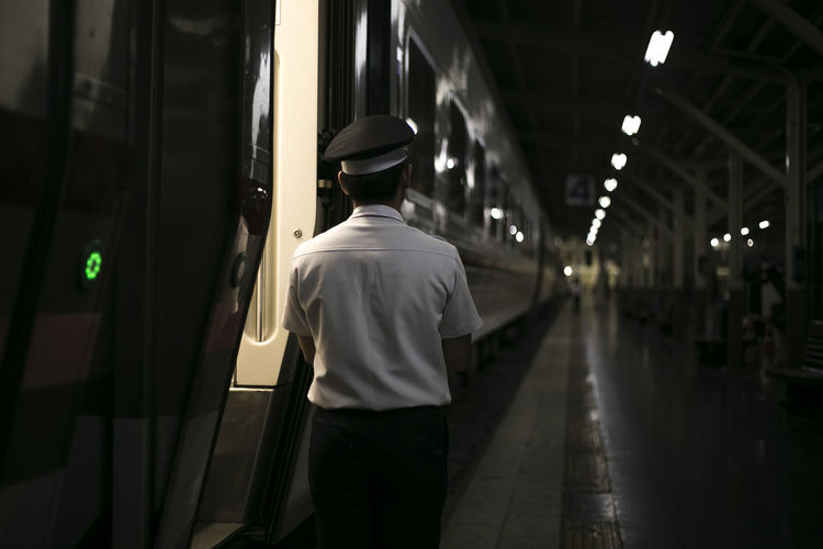 Rear view of men standing by train at railroad station platform
