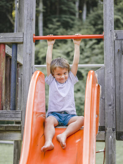 Portrait of smiling boy sliding at playground