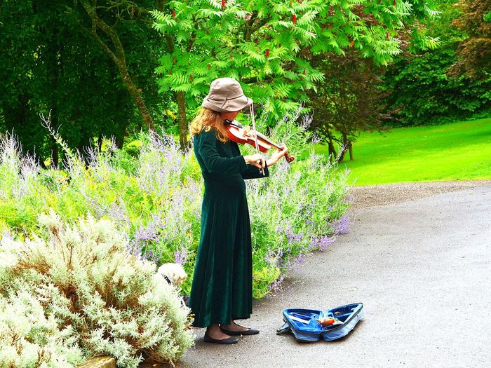 Woman playing violin by plants
