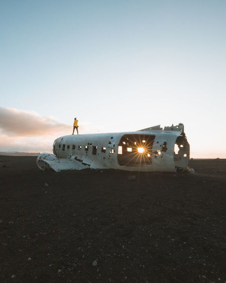 Abandoned airplane at beach against sky