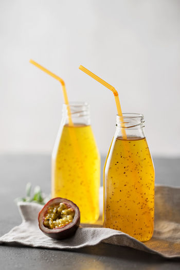 Passion fruit drink with chia seeds in glass bottles with tubes. grey background