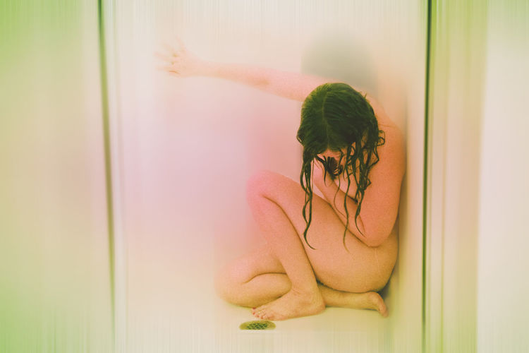 Naked woman sitting in bathroom
