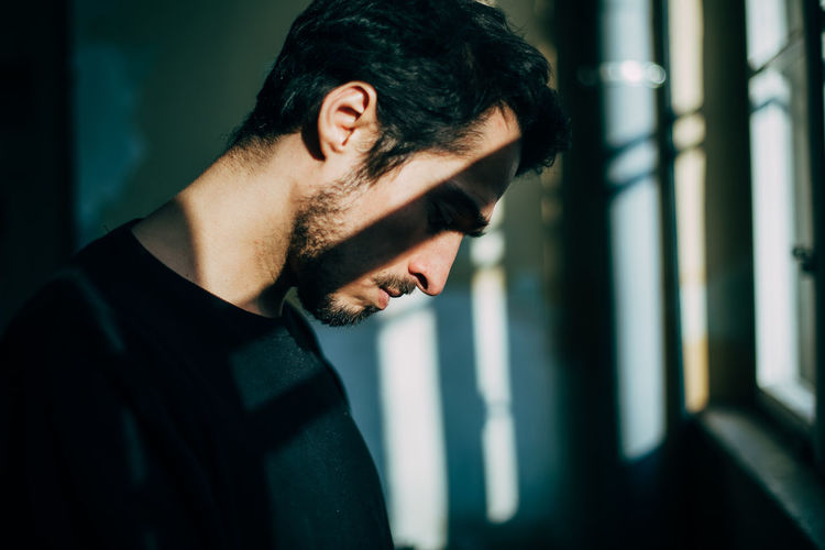 Close-up of young man by window