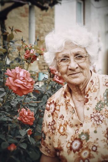 Portrait of senior woman standing by flowering plant