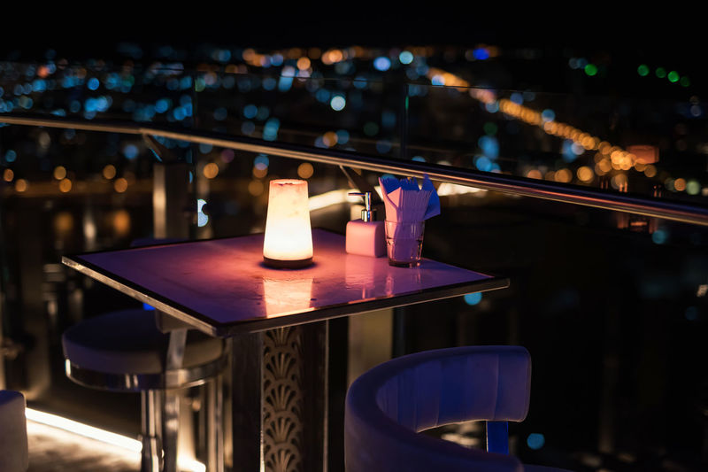 Open air dinner table at rooftop with blur bokeh city light background. luxury pub and restaurant