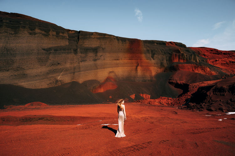 Full length of woman standing on soil against rock mountain