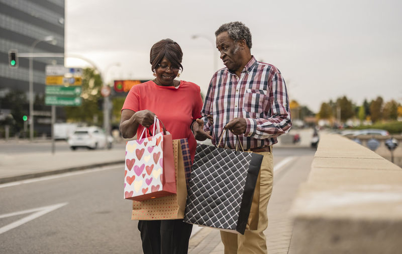 Senior couple talking to each other holding shopping bags