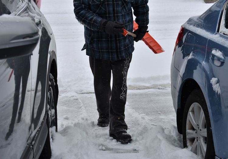 Low section of man cleaning on snow covered yard