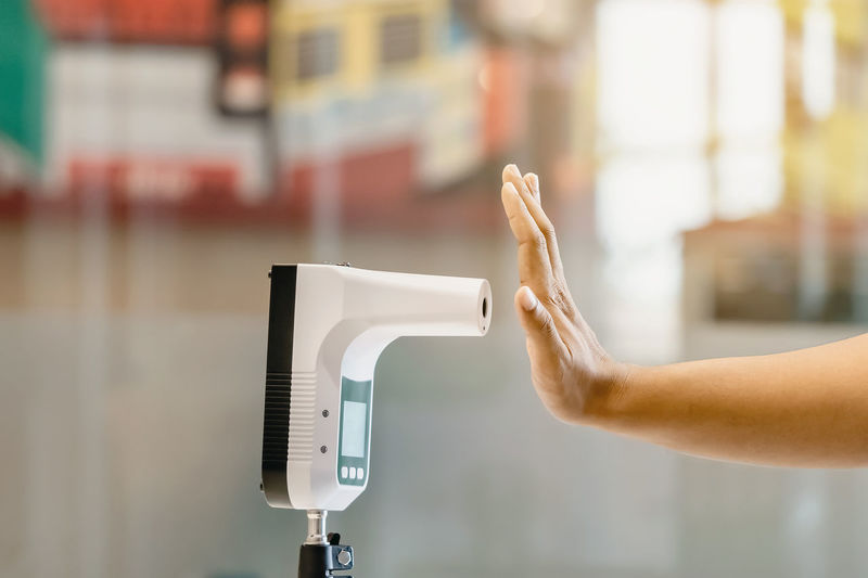 Customer raised hand at digital thermometer with temperature scanning machine for fever 