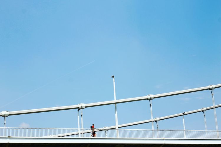 People on bridge against clear blue sky