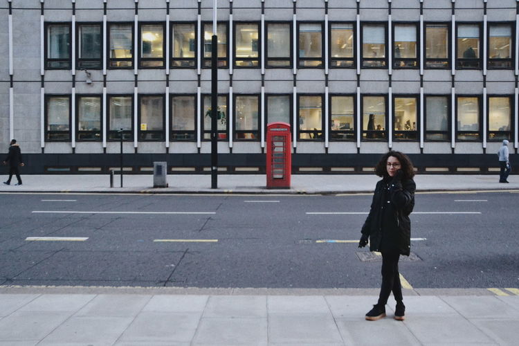 Full length of woman walking on sidewalk in city