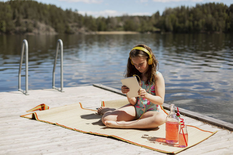 Girl using digital tablet on jetty