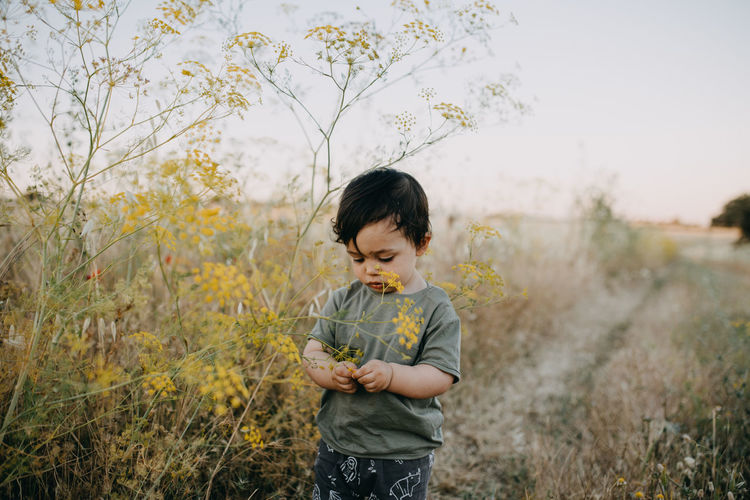 Boy standing by plant in field