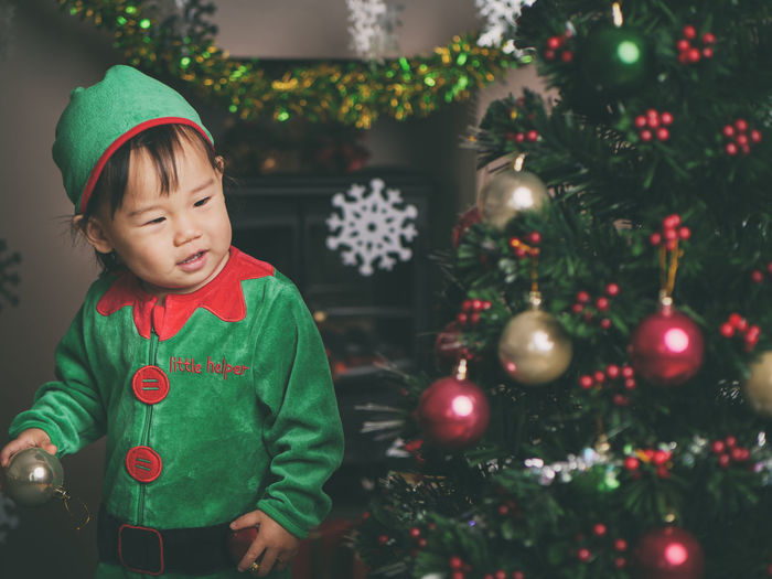 Cute baby girl by christmas tree at home