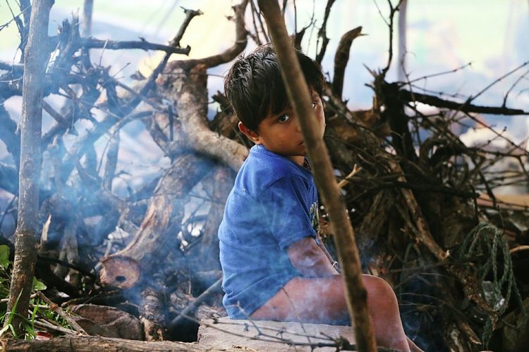 Young indian boy sitting by bonfire