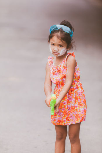 Portrait of cute girl holding squirt gun outdoors