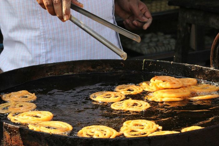 Midsection of vendor frying jalebis at store