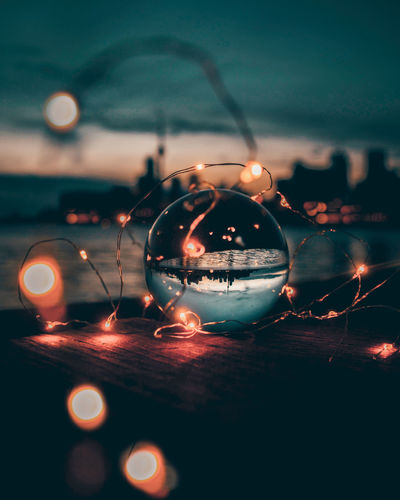 Illuminated string lights and crystal ball during dusk