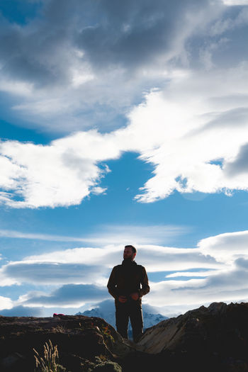 Man standing on rock against sky