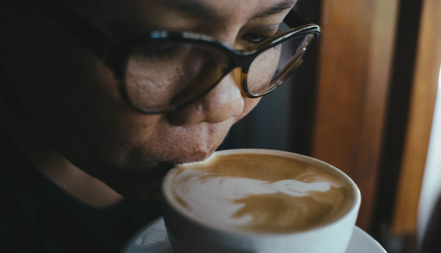 Close-up of woman drinking coffee from cup in cafe