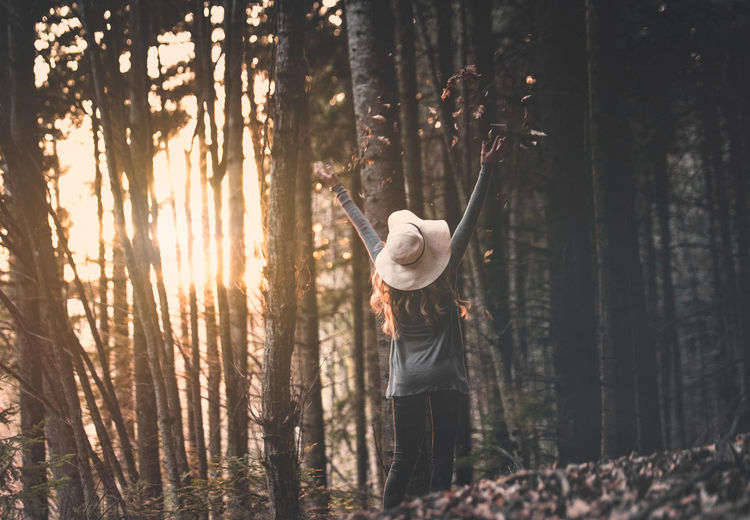 Rear view of woman with arms raised in forest