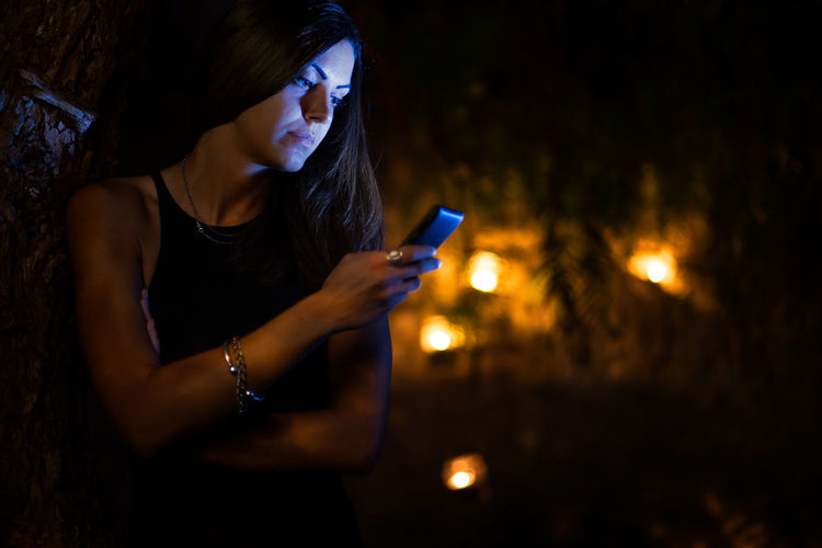 Young woman using mobile phone at night
