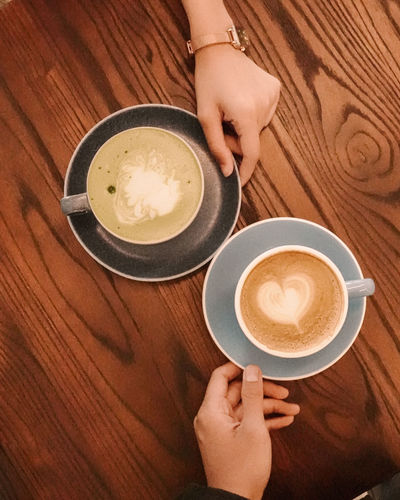 Cropped hands of woman holding coffee on table