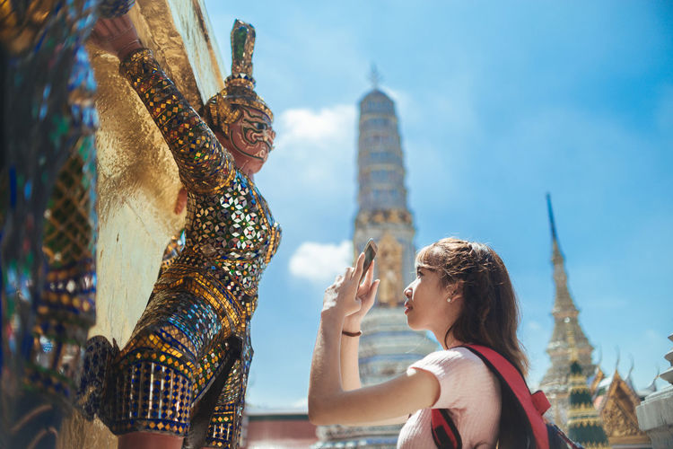 Woman photographing statue in city