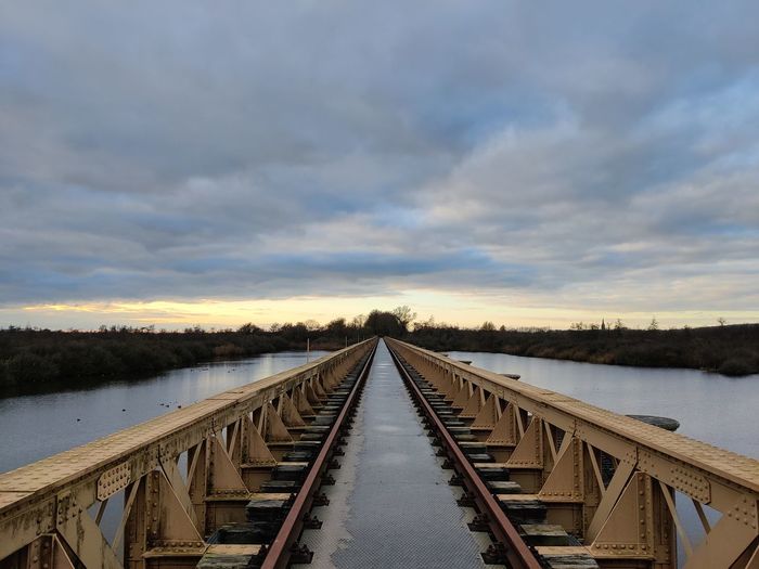 Bridge with rails above a lake sky