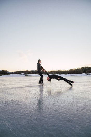 Two female figure skaters performing death spiral on frozen lake
