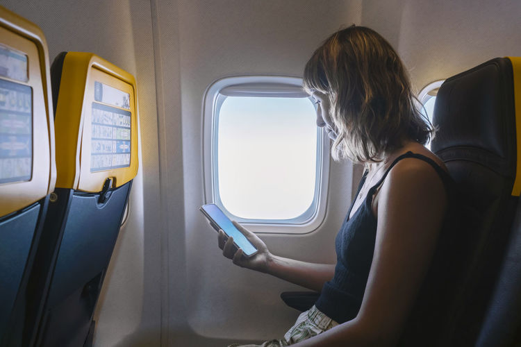 Woman using smart phone in airplane