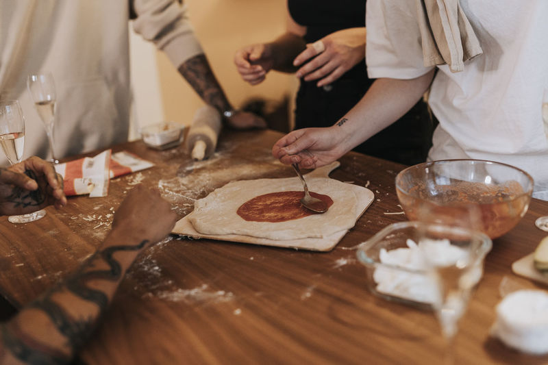 Mid section of people preparing pizza