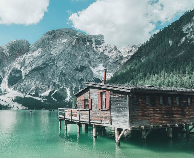 Built structure by lake and mountains against sky