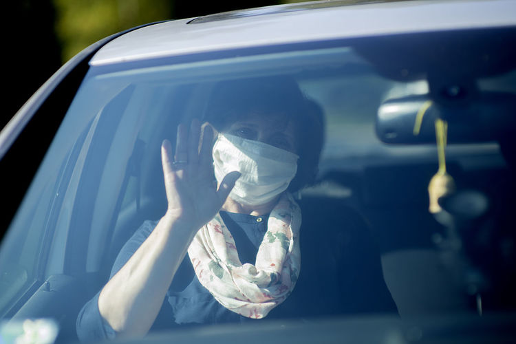 Elderly senior woman wearing a face mask while driving a car during covid-19 epidemic