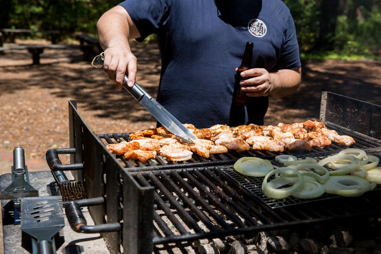 Midsection of man cooking food on barbecue