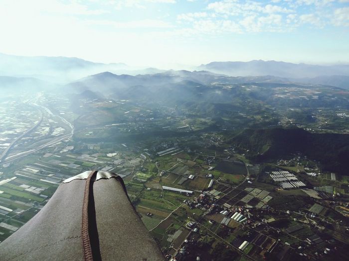 Cropped image of airplane wing flying over landscape