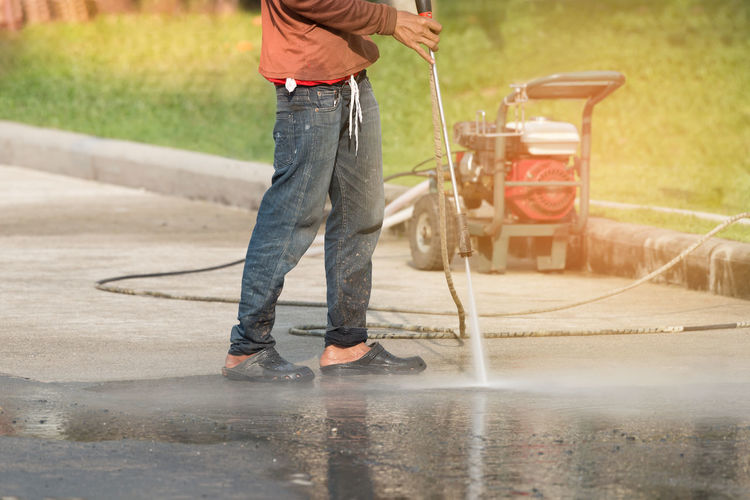 Low section of man washing concrete road